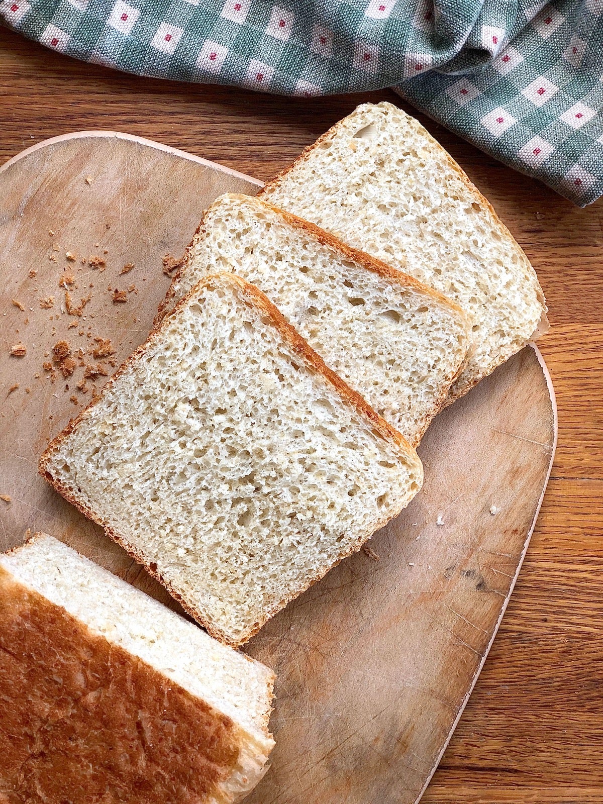 Oatmeal bread made in a pain de mie pan, sliced on a cutting board